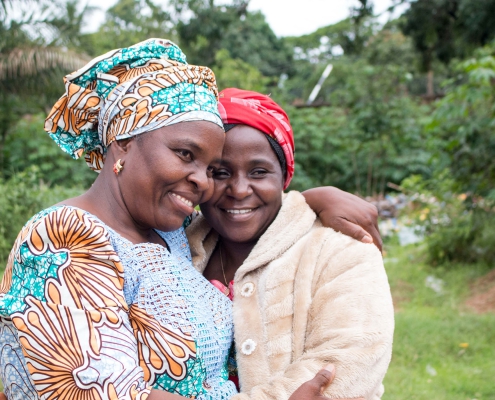 Two smiling ladies embrace with warm smiles