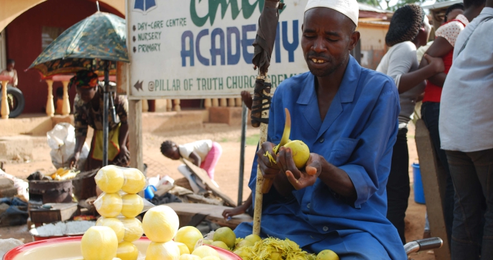 A man selling fresh produce on a street in Nigeria
