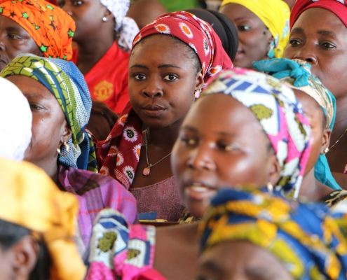 Closeup view of the faces of a group of women, all wearing colourful head coverings