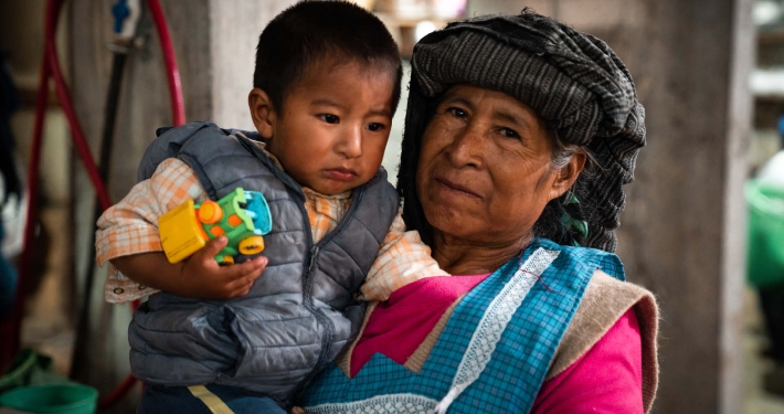 An elderly woman in traditional clothing holing her young grandchild in her arms