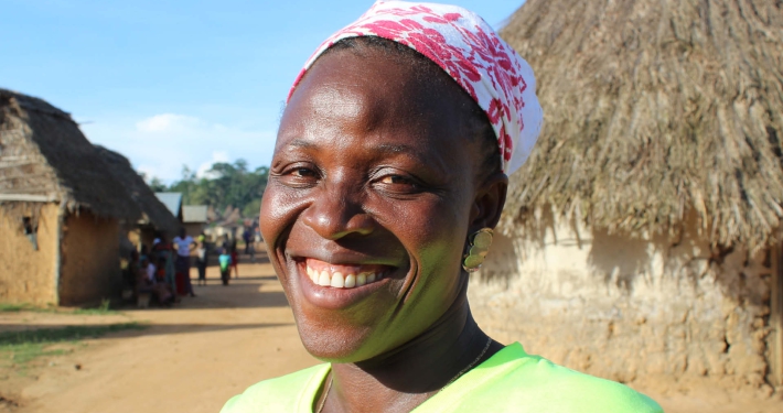 A smiling woman in a rural village setting, Guinea
