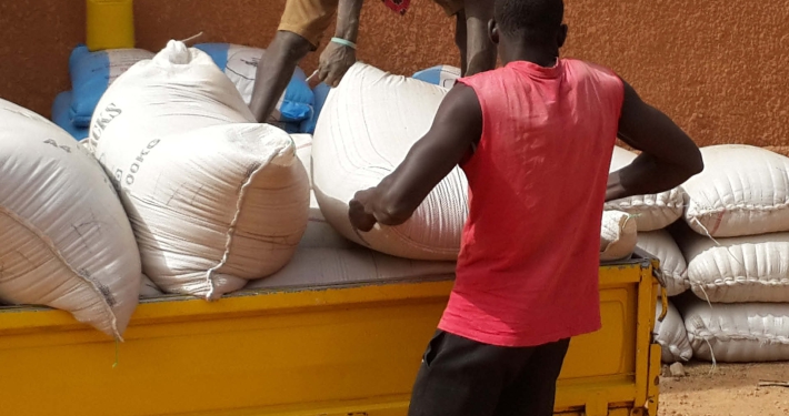 Two men unloading heavy sack of grain