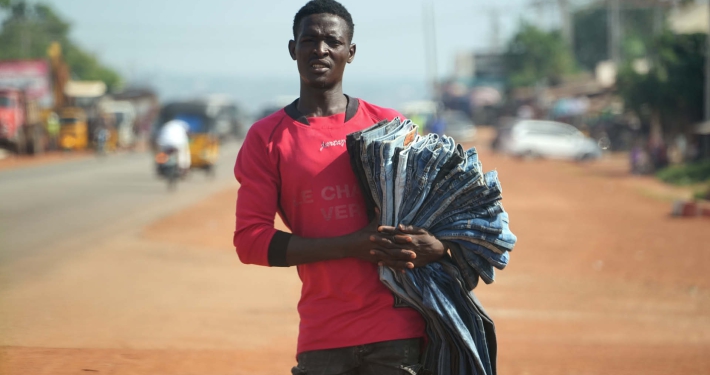 A street vendor holding a pile of denim jeans