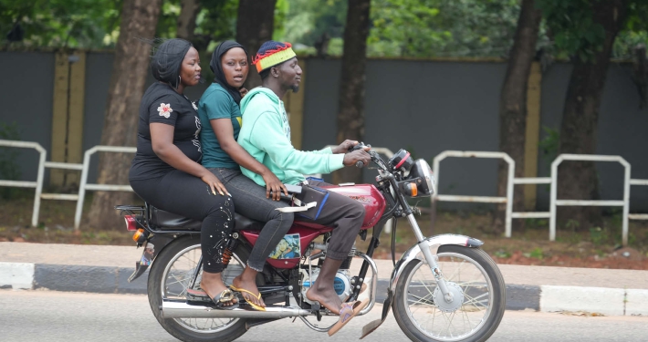 Two women catching a lift on a motorbike driven by a man